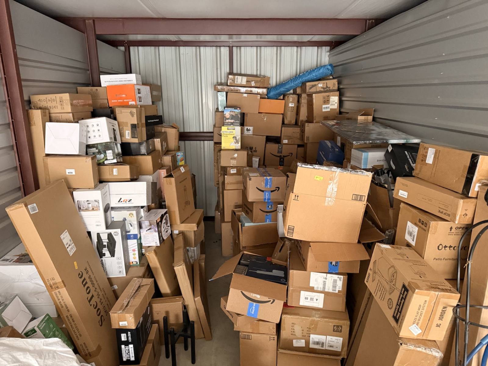 Second wide photo of bulk Amazon inventory and unopened boxes inside the storage unit